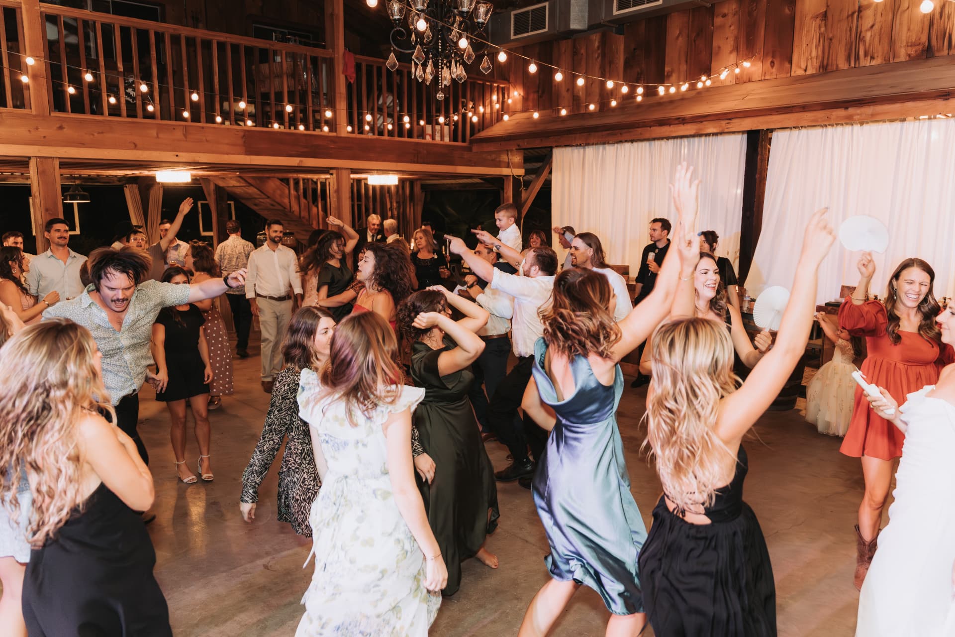 Full reception crowd dancing beneath a chandelier